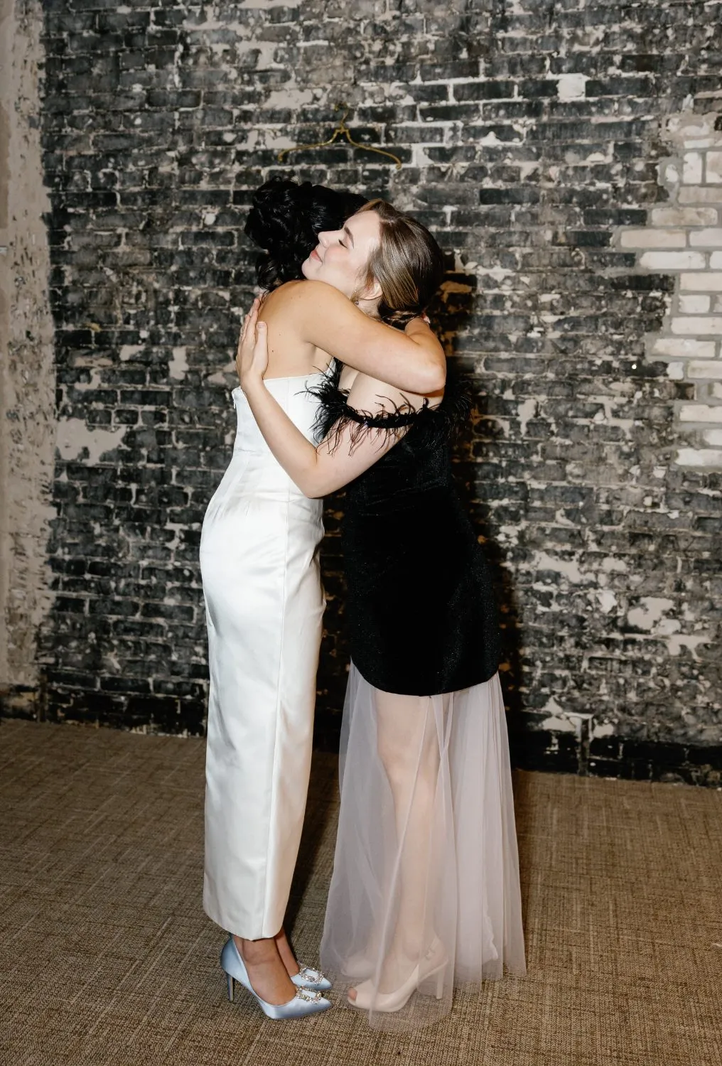 The bride and Aleksandra Safonova embracing after the ceremony, both in gowns from the atelier
